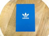 blue notebook with white adidas logo on it sitting on a wooden table