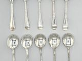 six silver spoons are arranged in a row on a white surface
