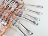 several forks and spoons are arranged on an orange and white plate