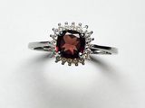 gros plan d'une bague avec une pierre rouge entourée de diamants blancs