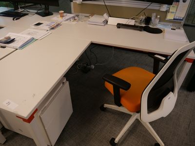 un bureau avec un écran d'ordinateur et une chaise devant
