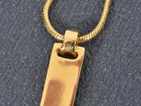 a close up of a gold pendant on a chain on a black surface
