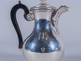 une cafetière ancienne en argent avec une poignée noire sur fond blanc