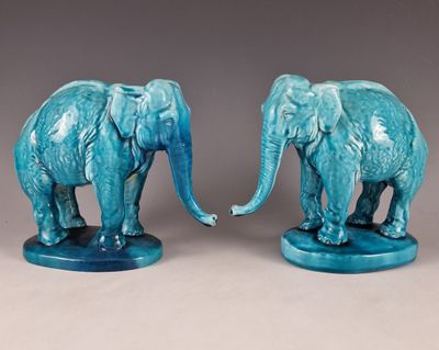 pair of blue ceramic elephant figurines on stand on grey background