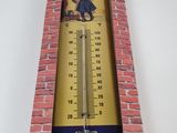 a thermometer hanging on a brick wall in a room