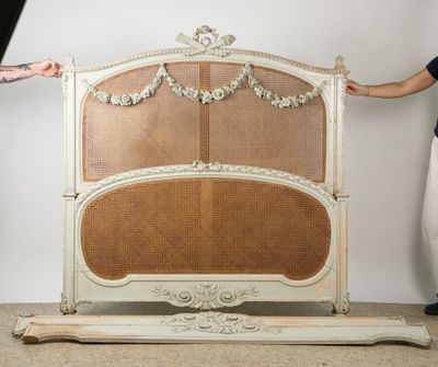 a woman standing next to a bed with a wicker headboard