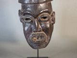 an image of a wooden mask on a stand on a white background