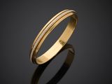 a gold wedding ring with diamonds on a black surface