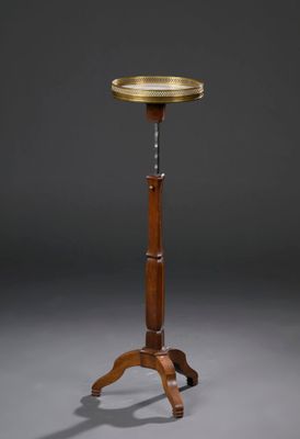 une plaque en laiton ancien posée sur une table trépied en bois