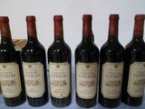 six bouteilles de vin sont alignées sur une surface bleue