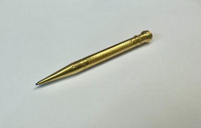 a gold colored pen sitting on top of a white table