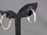 a pair of silver hoop earrings sitting on a black stand