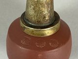 a brown vase with a gold top sitting on a white surface