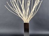 un grand vase contenant des fleurs blanches, posé sur une surface noire