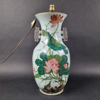 a white vase with a pink flower and green leaves on it