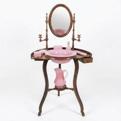 a pink vanity with a mirror and a pink vase