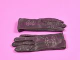 une paire de gants en cuir noir sur fond rose