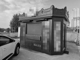 photo en noir et blanc d'un petit bâtiment devant lequel est garée une voiture