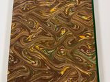 a close up of a brown and green marbled book on a white surface