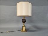 brass and wood table lamp with a white shade on a gray background
