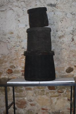 une pile de casseroles noires posée sur une table devant un mur de briques