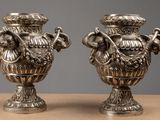 two silver vases that are sitting on a table