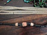 a beaded necklace with a wooden bead on a wooden table