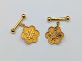 a pair of gold cufflinks with chinese characters on them