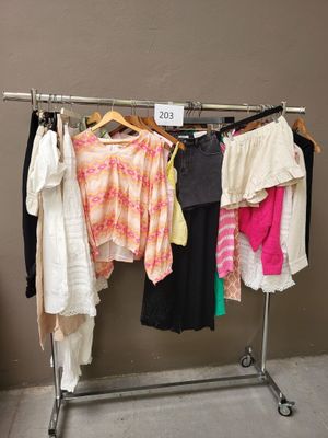 beaucoup de vêtements suspendus à une étagère dans une pièce