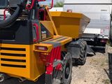 a yellow dump truck parked next to a white truck