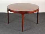 a round table with a wooden top on a carpeted floor