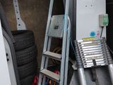 une échelle appuyée contre un mur, à côté d'une autre échelle
