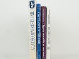 three books are stacked on top of each other on a white surface