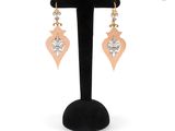 a pair of earrings on a black stand with a white background