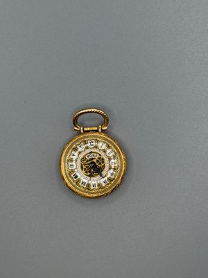 une image représentant une montre de poche en or posée sur une surface grise
