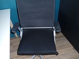 a black office chair sitting in front of a blue wall
