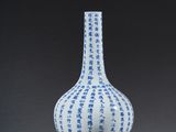blue and white vase with a red stand on a gray surface