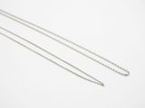 a close up of two silver chains on a white surface