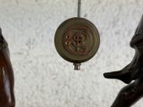 a clock hanging from the side of a statue of a man