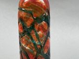 a red and green vase that is sitting on a table