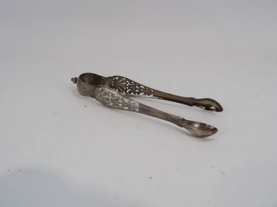 une cuillère et une pince en argent posées sur une surface blanche