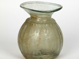 un petit vase en verre avec un socle vert sur fond blanc