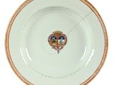 an image of a white plate with a gold rim and a coat of arms on it