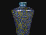 vase bleu et vert sur une surface noire, avec un fond noir