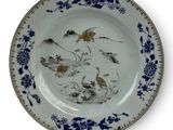a blue and white plate with birds and flowers on it