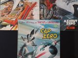 trois livres posés sur une surface noire, avec l'image d'un avion en arrière-plan