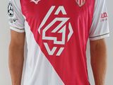 Le jeune homme porte un maillot de foot rouge et blanc.