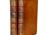 an old book with a leather cover sitting on top of a white surface