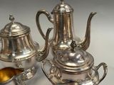 three pieces of silver tea and coffee set on a table