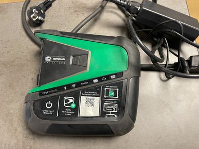 un chargeur de batterie vert et noir posé par terre